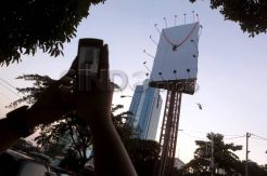 Seorang pria terbelit tali di atas papan reklame setinggi 25 meter